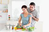 Man massaging his wife while she is cutting vegetables