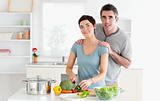 Husband massaging his wife while she is cutting vegetables