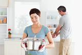 Cute Woman holding a pot while man is washing the dishes