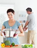 Cute wife holding a pot while her husband is washing the dishes