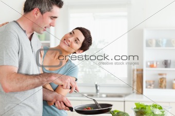 Woman smiling at her pan-holding husband