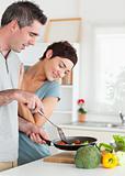 Charming Woman looking into a pan her husband is holding