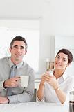 Smiling couple drinking coffee looking into the camera