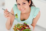 Cute young woman eating salad