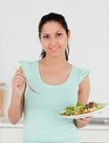 Young woman standing in kitchen with salad