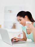 Young woman with cup of coffee at by her laptop