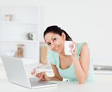 Smiling young woman with coffee by laptop