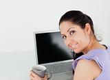 Cheerful young woman with coffee by laptop