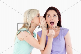 Portrait of a blond woman telling her friend a secret
