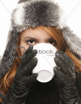 young woman in winter dress drinking coffee or tea from a cup