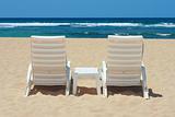Two sun beach chairs on beach sand near ocean