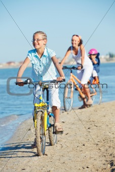Cute girl with her mother and brother ride bikes