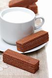 Cup of milk and chocolate wafers on a linen napkin.