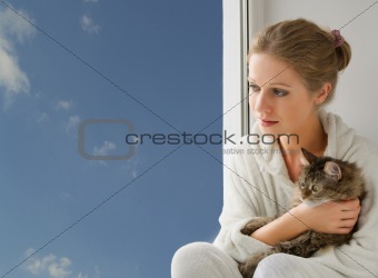 girl with a cat looking out the window