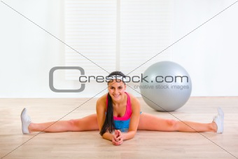 Smiling gymnastic girl siting on gym split
