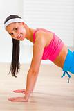 Smiling flexible young girl making push-up exercises
