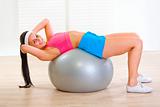 Smiling fitness girl doing abdominal crunch on fitness ball
