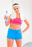 Smiling girl with towel around neck holding bottle of water 
