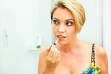Beautiful woman in bathroom applying lipstick
