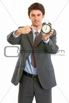 Modern businessman pointing on alarm clock
