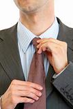 Businessman straightens tie. Closeup
