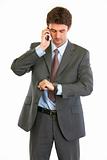 Modern businessman talking on phone and looking on watch
