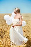 Beautiful girl with white balloons in the field