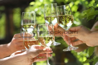 People holding glasses of white wine making a toast