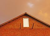 Fragment of brick house in the background reddish thunderclouds.