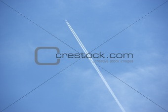 White Condensation Trail From A Jet As It Flies Across A Blue Sky