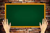 hand holding green blackboard on grunge wall