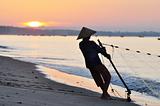 Silhouette of a fisherman on beach at sunrise