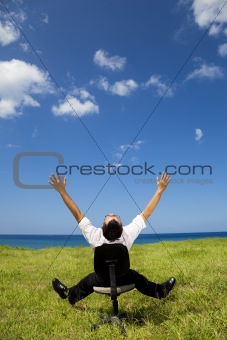 relaxed businessman sitting on the chair in green field