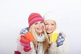 Two pretty happy winter girls friends drinking hot tea
