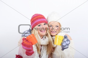 Two pretty happy winter girls friends drinking hot tea