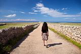 woman walking rural road to lighthouse