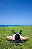 Businessman lying on green grass and watching the blue sky