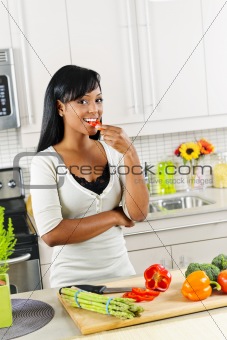Young woman tasting vegetables in kitchen