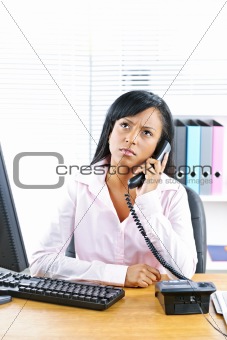 Concerned black businesswoman on phone at desk