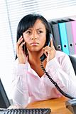 Black businesswoman using two phones at desk
