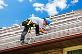 Man working on roof installing rails for solar panels