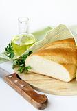 fresh white loaf of bread with a knife , olive oil , rustic style