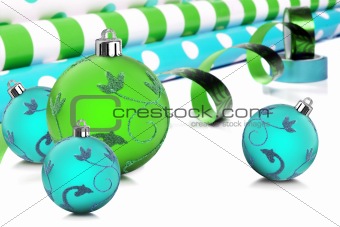 Rolls of gift wrapping paper and ribbon with blue and green christmas baubles