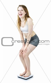 Excited fit young girl on bathroom scale