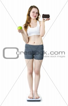 Young girl on scale holding apple and cake