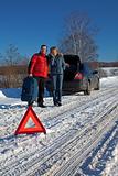 Man And Woman Broken Down On Country Road With Hazard Warning Sign