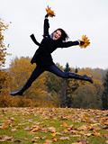  beautiful girl with autumn leafs in a park jumping and smiling