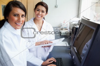 Smiling scientists posing with a monitor