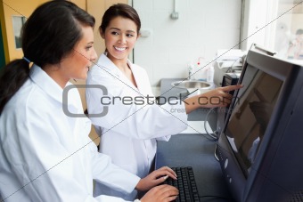 Smiling female scientists working with a monitor