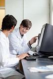 Scientist pointing at something on a monitor to his colleague
